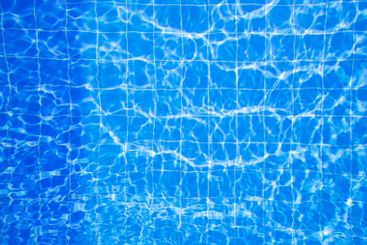 Clear blue water with sunlight reflections creating...