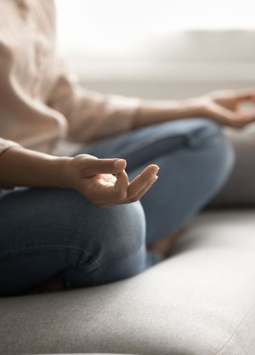 Closeup young woman sit on couch rest do yoga meditate