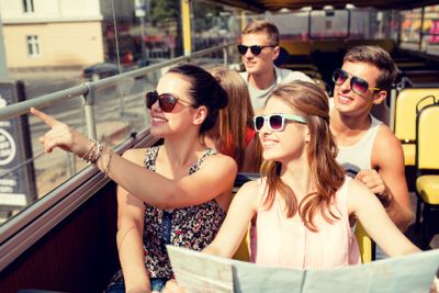 group of smiling friends traveling by tour bus