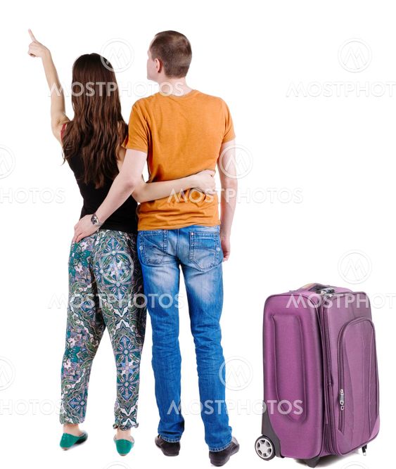 young couple traveling with suitcas and pointing at wal...