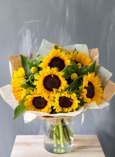 Bouquet of sunflowers and wild flowers on wooden table,...