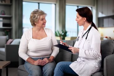 Doctor Talking To Elderly Patient At Home