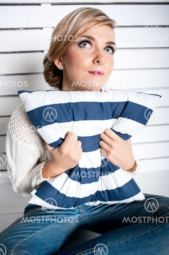 The young girl dreams sitting on a floor and squeezes a pillow