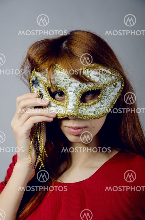 Beautiful young girl in a red dress and mask