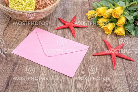 Envelope, starfishes and roses on a wooden background