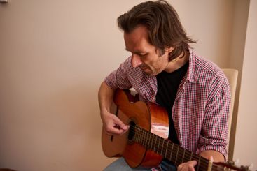 Man Playing an Acoustic Guitar in a Casual Indoor Setting