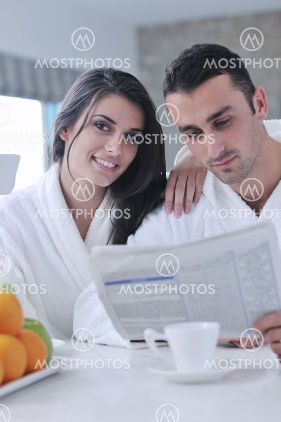 Happy couple reading the newspaper in the kitchen at breakfast