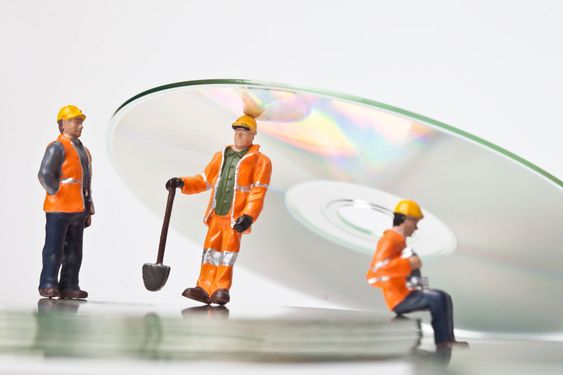 Miniature people in action with CDs