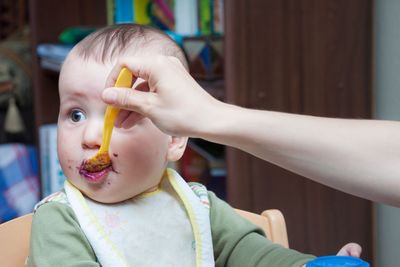 Mother feeding a funny looking baby with a spoon with...