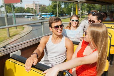 group of smiling friends traveling by tour bus
