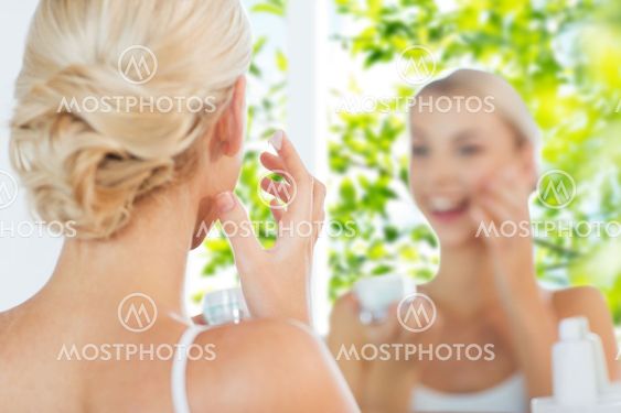 close up of woman applying face cream at bathroom