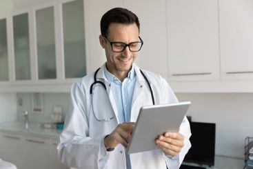Happy male physician doctor reading medical reports on...