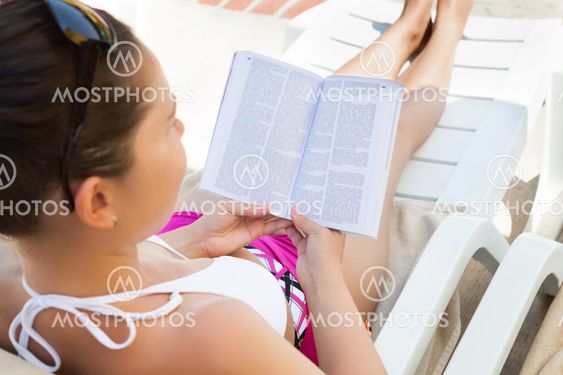 Woman Reading Book On Lounge Chair At Resort