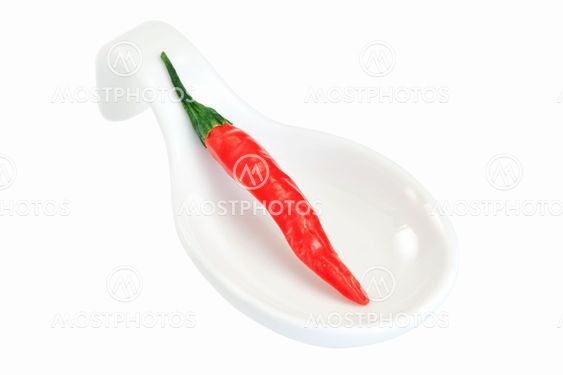 The fruit of chili peppers on a porcelain spoon. On a...
