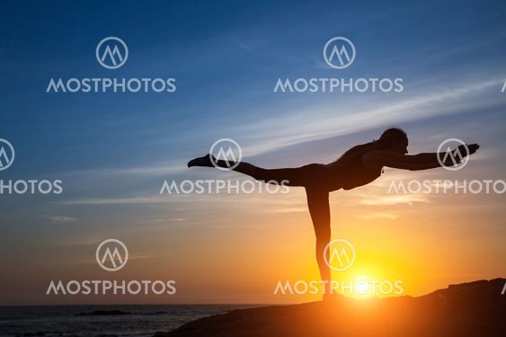Silhouette of woman doing fitness exercise on the sea beach during amazing sunset.