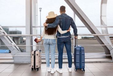 Rear View Of Romantic Couple Looking Out Of Window At...