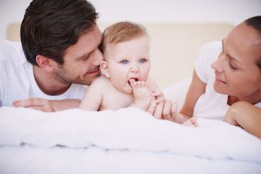 Love, parents and relax with baby in bed for playing...