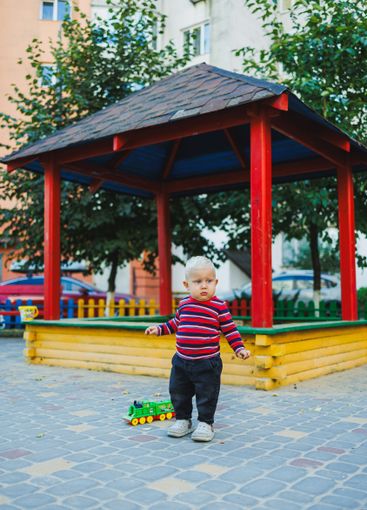 A fair-haired one-year-old boy in jeans and sneakers...