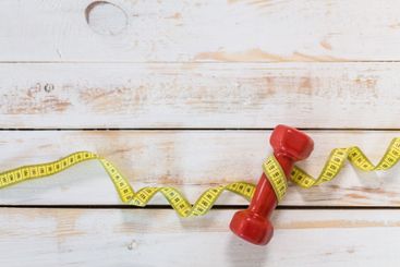 Fitness concept with dumbbells and measuring tape