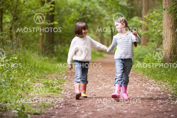 Two sisters walking on path holding hands smiling
