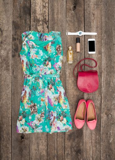 Colorful floral dress and accessories arranged on wooden...