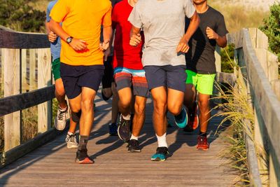Group of teenagers running on a boardwalk in sunshine