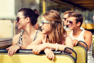group of smiling friends traveling by tour bus