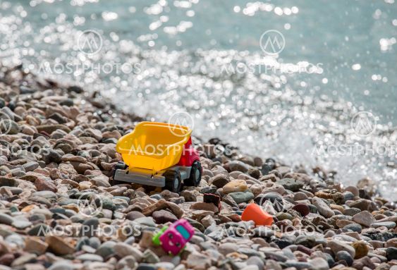 Bright plastic baby toy cars on a pebble beach near the...