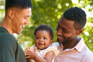 Loving Same Sex Male Couple Or Friends Cuddling Baby...