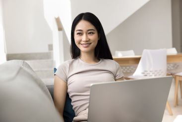 Asian woman relaxed and contented sit on sofa with laptop