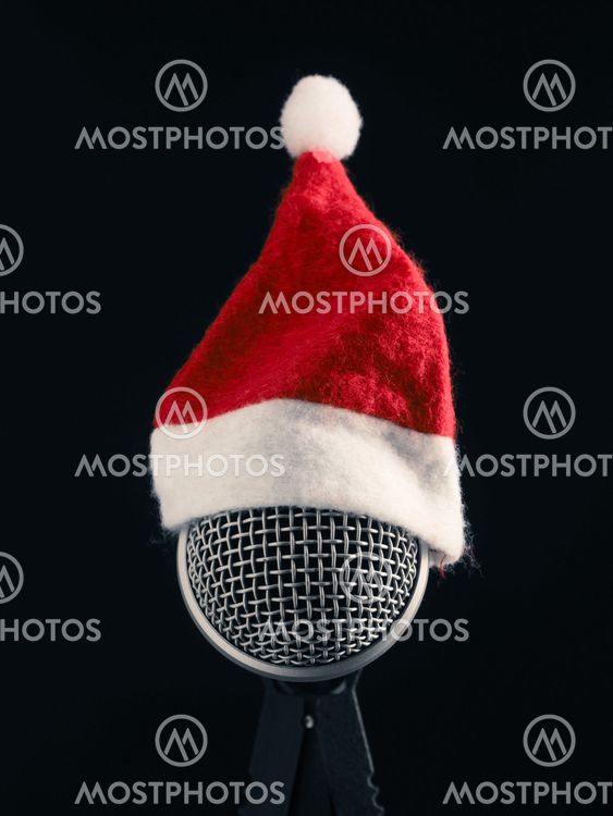 Close up of a microphone with the hat of Santa on a dark...