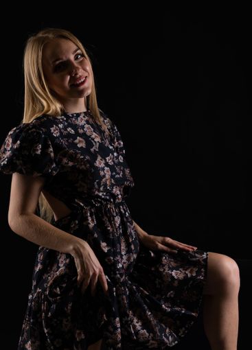 Beautiful blonde woman in summer dark dress on black...