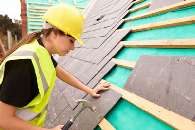 Female Construction Worker On Site Laying Slate Tiles