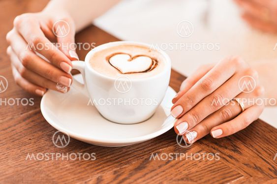 woman holding hot cup of coffee, with heart shape