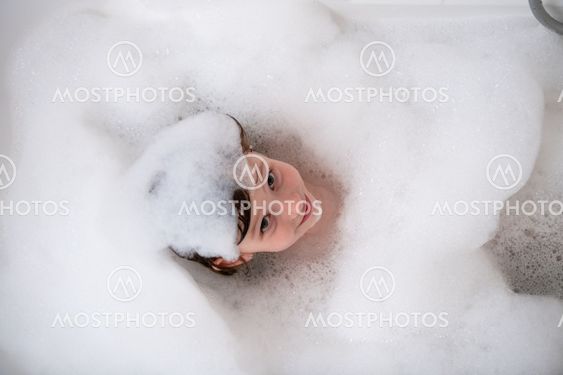 top view of little girl in bath playing with foam