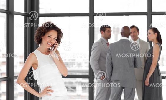 Bright Businesswoman holding a phone at workplace with his colleagues