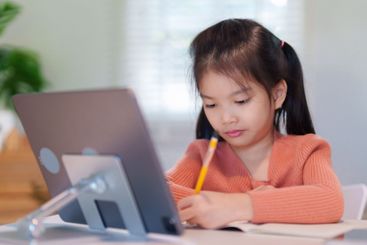 A young girl is concentrating on her homework with a...