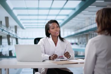 Unhappy doctor sits in a disciplinary meeting with black...