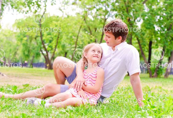 Father and daughter sitting together on the grass