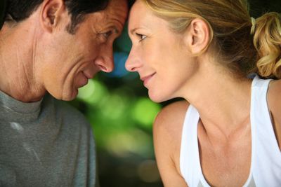 Head and shoulders of mature romantic couple looking at...