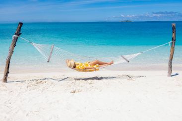 A young woman in a straw hat and a summer dress is lying...