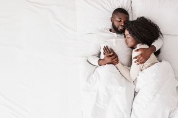 Black family couple lying and cuddling in bed, sleeping...