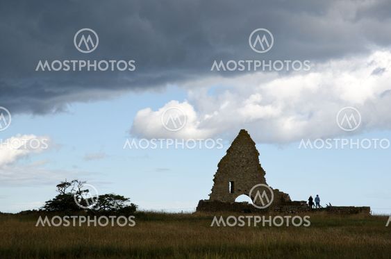 Turister kigge på et Kapel ruin med en sky af mørke skyer