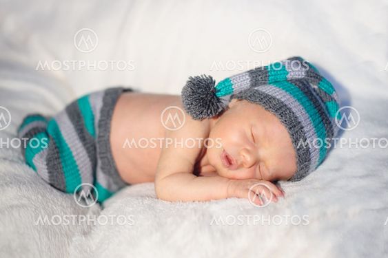 little baby boy in knitted hat lying on the bed