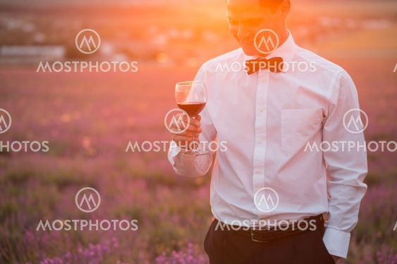 Elegant young guy drinking wine on sunset