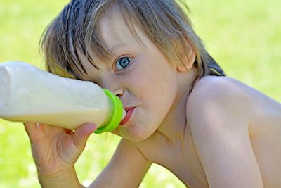 young boy eating from a feeding bottle