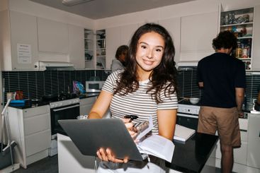 Portrait of smiling female students holding laptop and...