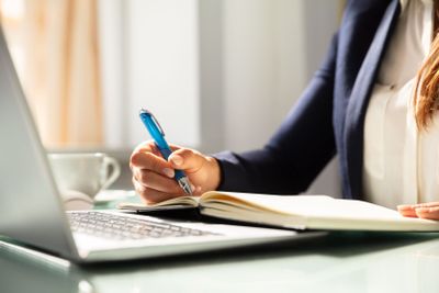 Close-up Of A Businesswoman's Hand Writing Note In Diary