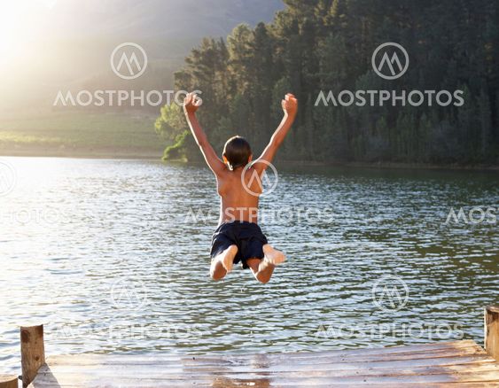 Young boy jumping into lake