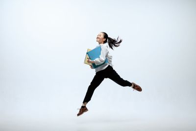 Woman working at office and jumping isolated on studio...